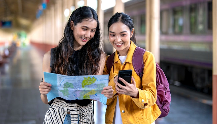 Two women examining a map for budget travel planning.