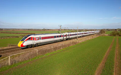 Train traveling through countryside on the National Rail network in England.