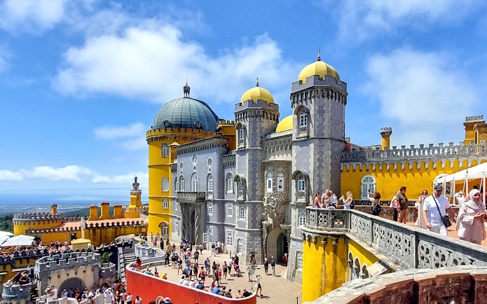 Pena Palace in Sintra with tourists exploring the colorful architecture.