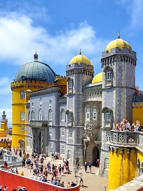 Pena Palace in Sintra with tourists exploring the colorful architecture.