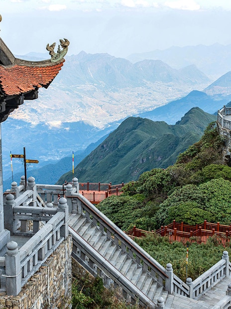 Terraced steps leading to a statue at Sun World Fansipan Legend, Vietnam, with mountain views.