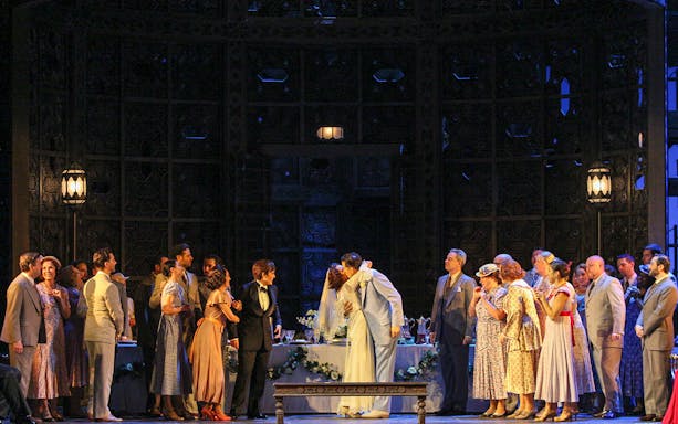 Wedding scene from Le Nozze Di Figaro opera with cast in period costumes on stage.