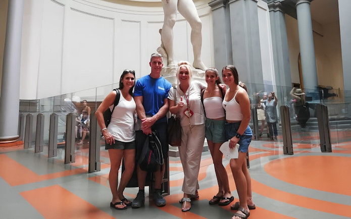 Tour group with guide in front of Michelangelo's David sculpture in Florence museum.