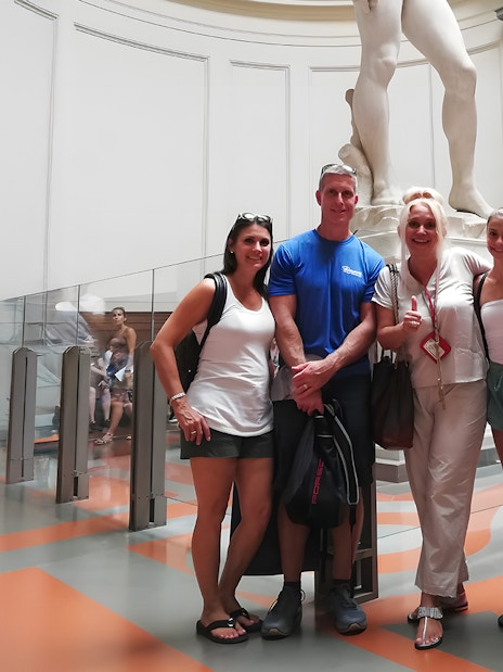 Tour group with guide in front of Michelangelo's David sculpture in Florence museum.