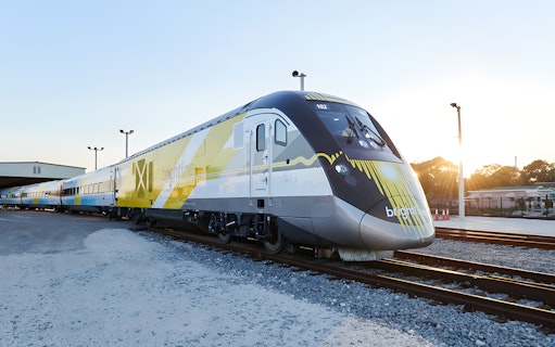 Brightline train exterior on tracks at sunset.