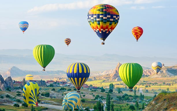 Hot air balloons over Cappadocia's fairy chimneys at sunrise.