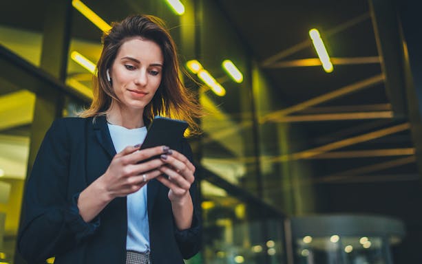 Person using smartphone with Malaysia 4G eSIM card in urban setting.