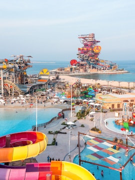 Aerial view of colorful water slides and pools at Meryal Waterpark by the sea.