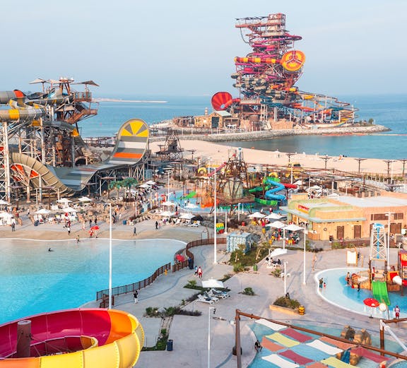 Aerial view of colorful water slides and pools at Meryal Waterpark by the sea.