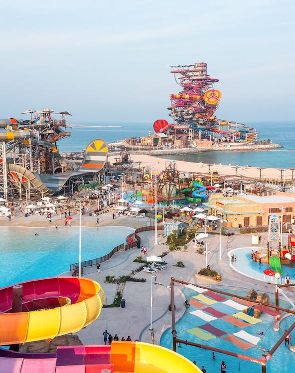 Aerial view of colorful water slides and pools at Meryal Waterpark by the sea.