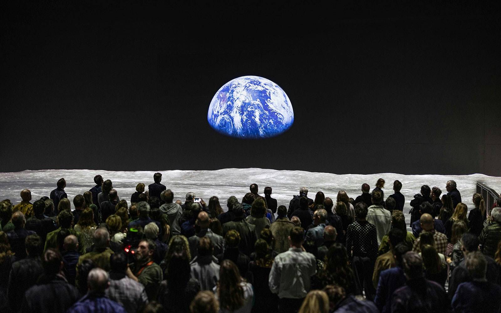 Crowd viewing Earth from Moon at The Moonwalkers immersive experience.