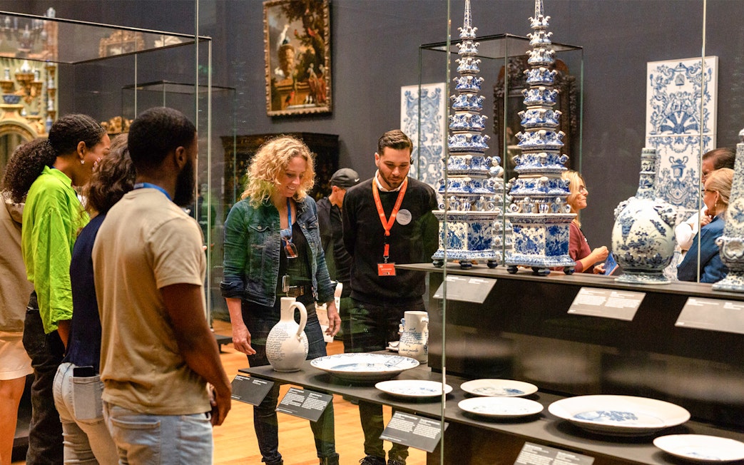 Visitors observing Delftware pottery on a guided tour at the Rijksmuseum, Amsterdam.