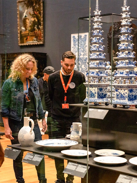 Visitors observing Delftware pottery on a guided tour at the Rijksmuseum, Amsterdam.