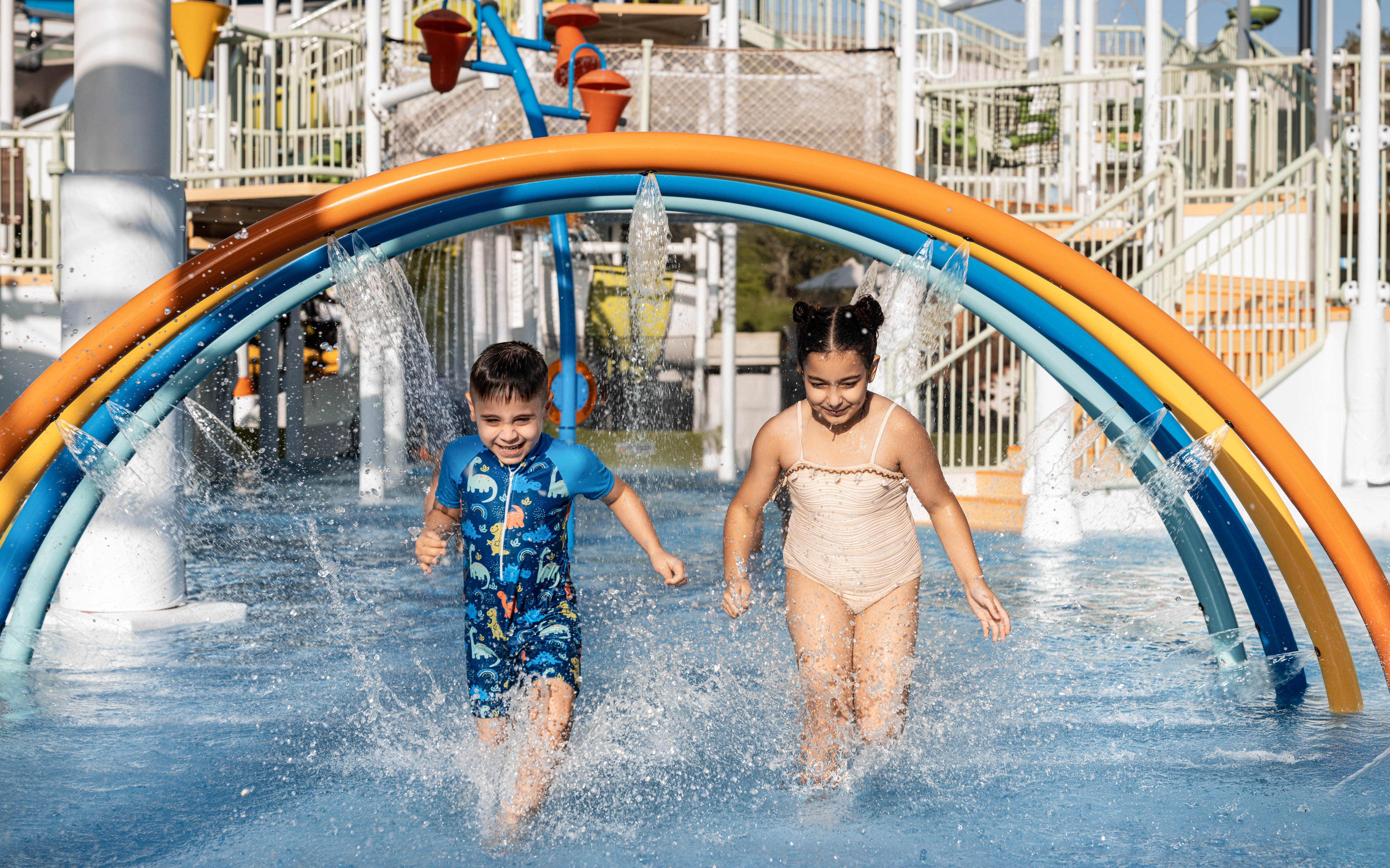 Children enjoying rainbow water arches at Grand Hyatt waterpark, Dubai.