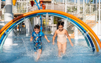 Children enjoying rainbow water arches at Grand Hyatt waterpark, Dubai.