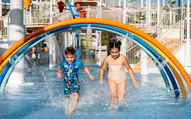 Children enjoying rainbow water arches at Grand Hyatt waterpark, Dubai.