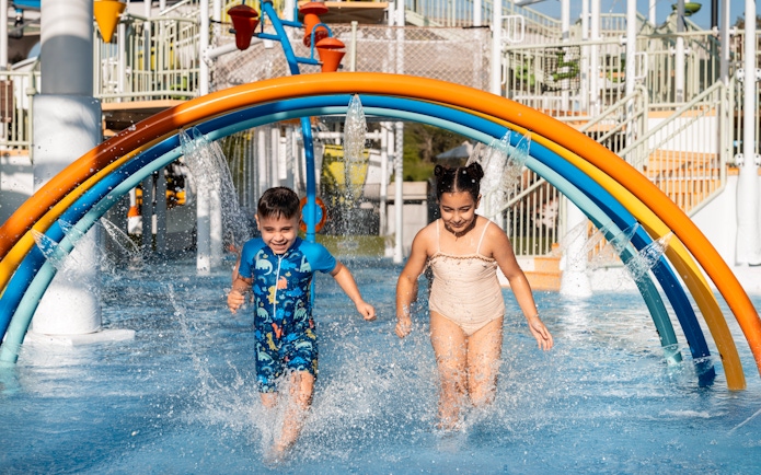 Children enjoying rainbow water arches at Grand Hyatt waterpark, Dubai.