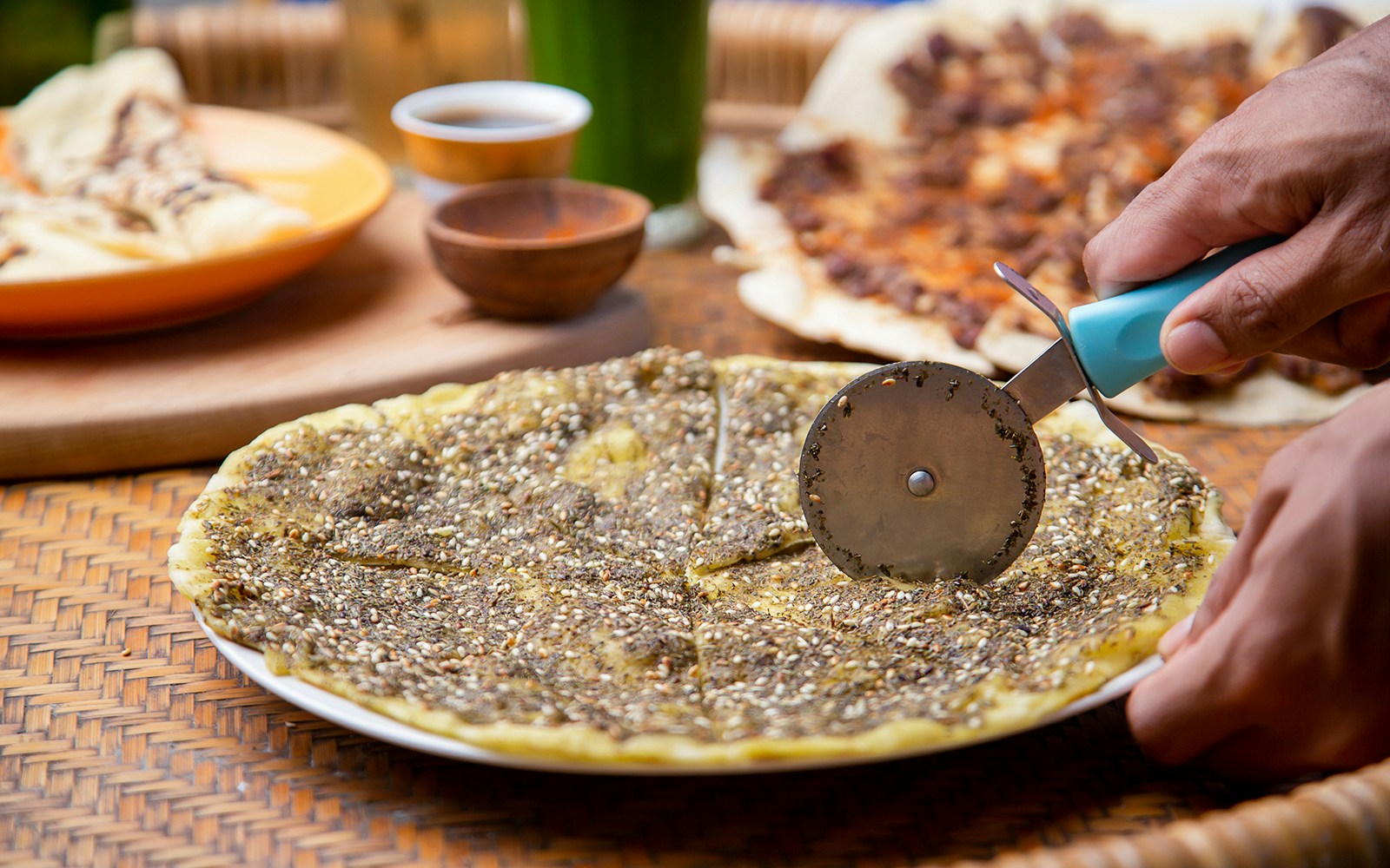 Manakish being sliced with a pizza cutter in Dubai.