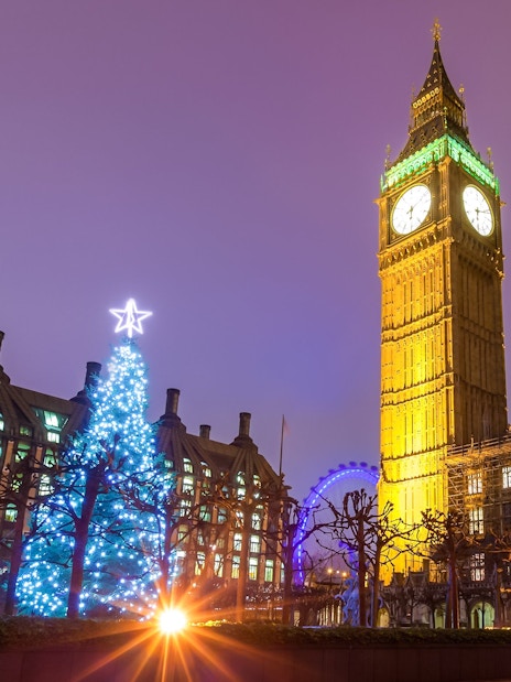 Big Ben and Christmas tree lights in London at night.