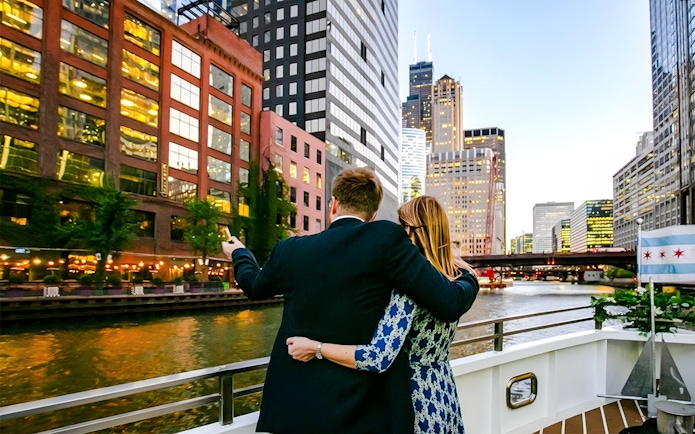 Couple on deck enjoying Chicago skyline during 90-minute scenic sunset Lake Michigan cruise.