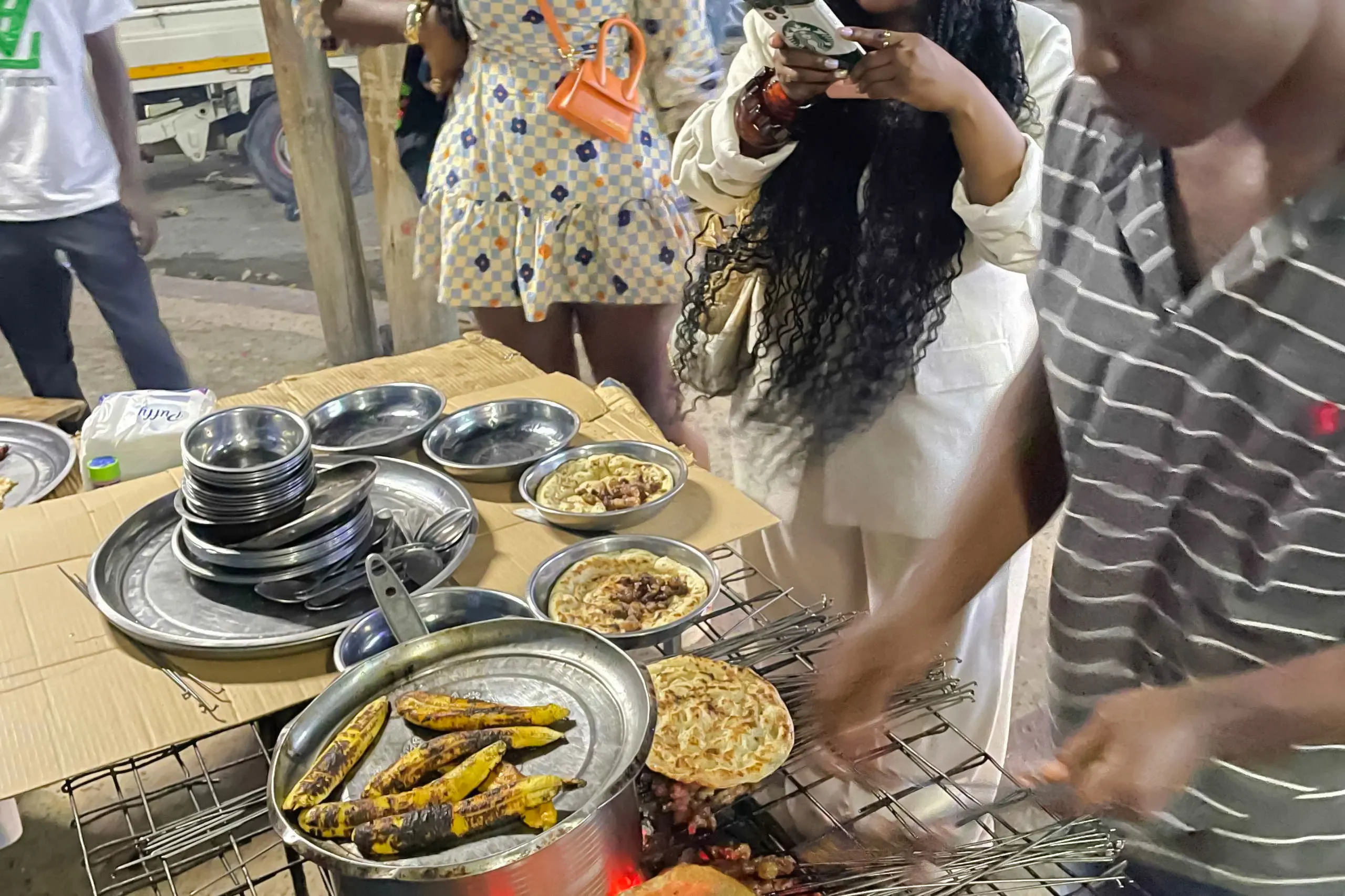 Street food preparation with grilled bananas and flatbreads during a Dar es Salaam food tour.