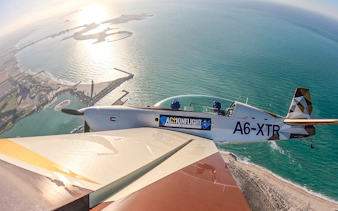 Aerobatic plane flying over coastal landscape during GFORCE Aerobatic Passenger Experience.