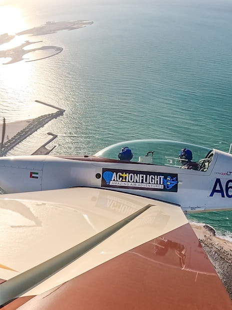 Aerobatic plane flying over coastal landscape during GFORCE Aerobatic Passenger Experience.