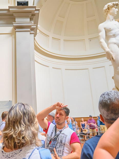 Tour group with guide at Accademia Gallery, Florence, viewing Michelangelo's David statue.