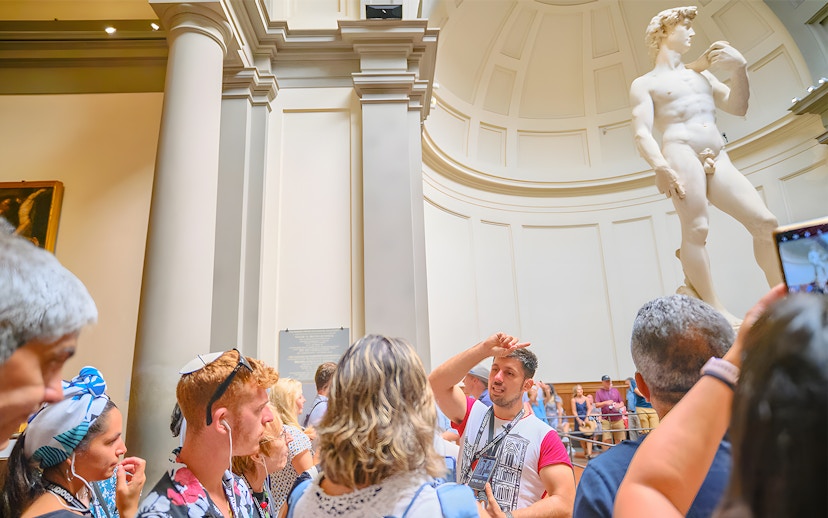 Tour group with guide at Accademia Gallery, Florence, viewing Michelangelo's David statue.