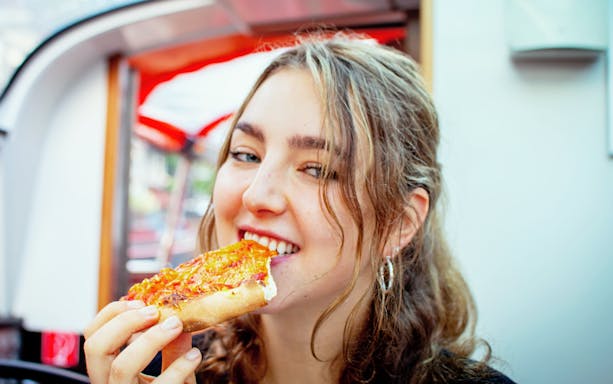Girl enjoying pizza on Stockholm pizza cruise.