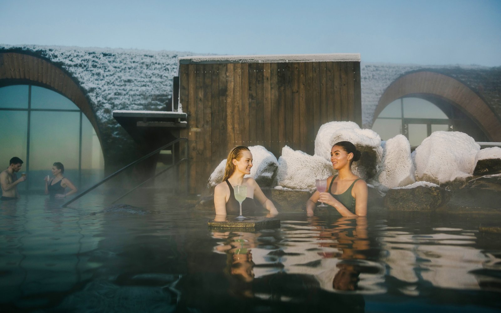Guests enjoying drinks at the lagoon bar in Laugarás Lagoon, Iceland.