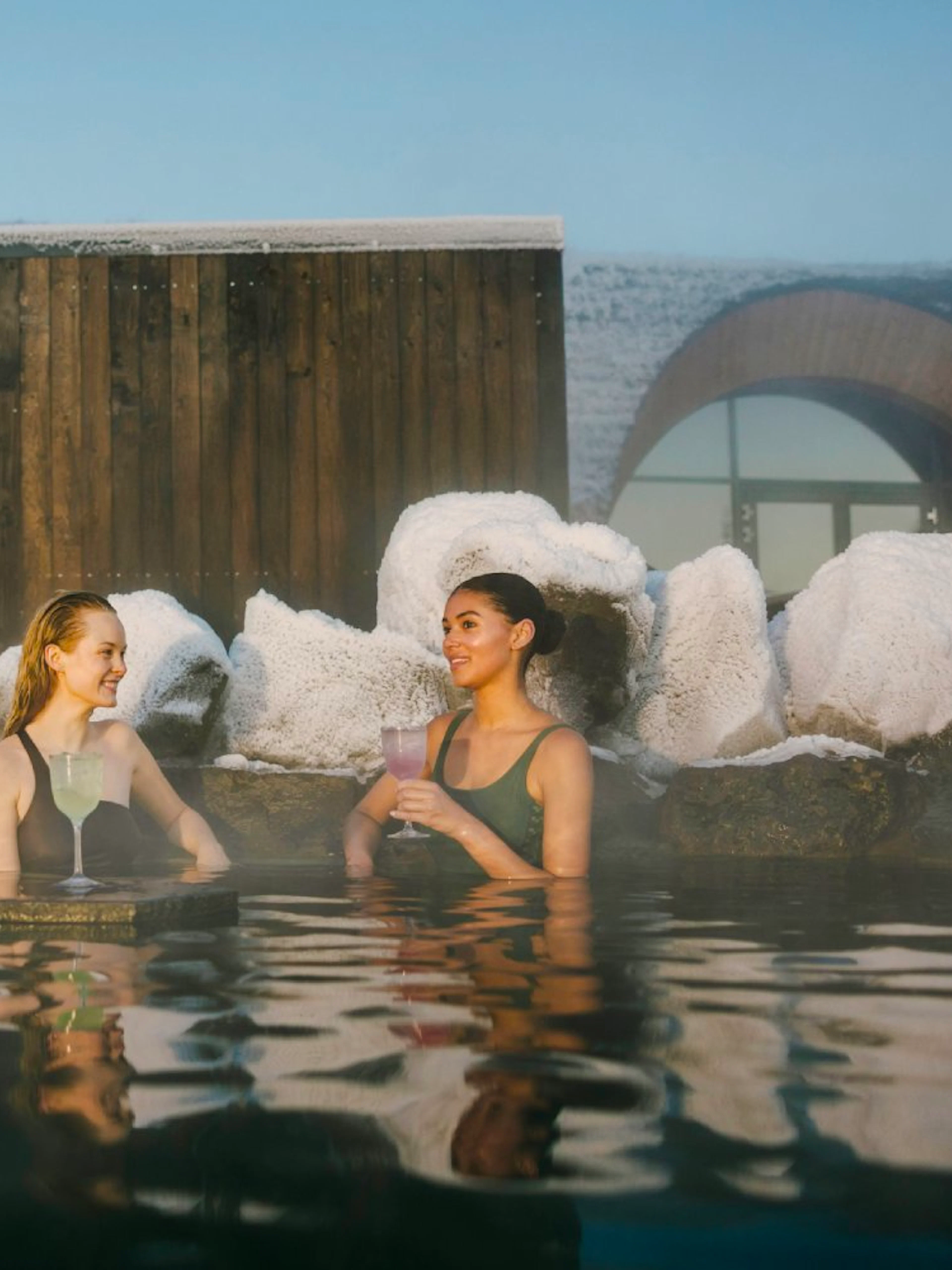 Guests enjoying drinks at the lagoon bar in Laugarás Lagoon, Iceland.