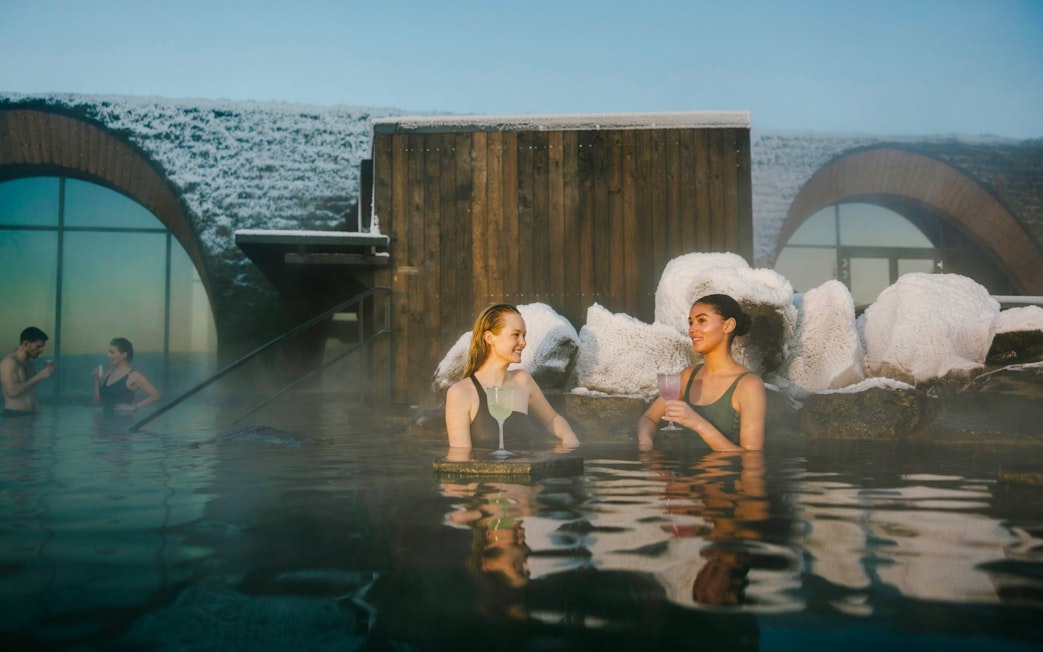 Guests enjoying drinks at the lagoon bar in Laugarás Lagoon, Iceland.