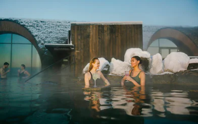 Guests enjoying drinks at the lagoon bar in Laugarás Lagoon, Iceland.