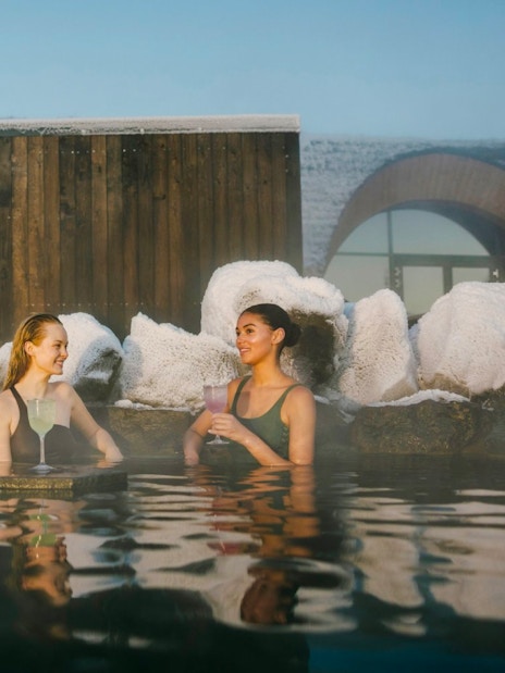 Guests enjoying drinks at the lagoon bar in Laugarás Lagoon, Iceland.