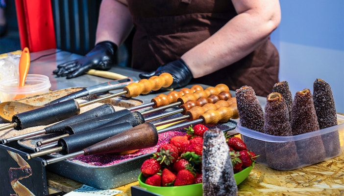 Churros preparation at a Madrid street market with strawberries and cooking tools.
