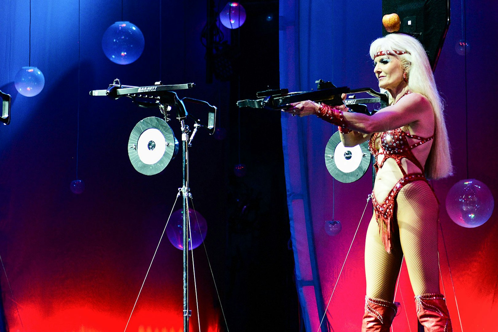 Performer aiming crossbow on stage at WOW: The Vegas Spectacular.