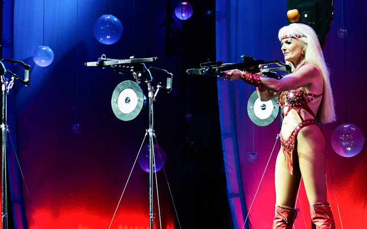 Performer aiming crossbow on stage at WOW: The Vegas Spectacular.