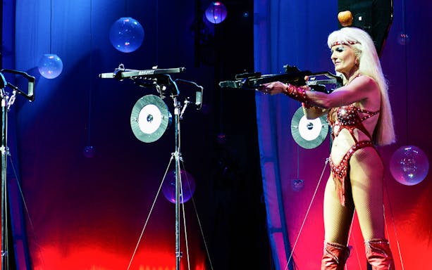 Performer aiming crossbow on stage at WOW: The Vegas Spectacular.
