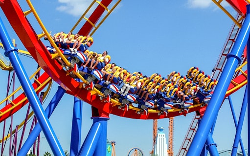 Visitors riding a colorful roller coaster at Parque Warner Madrid.