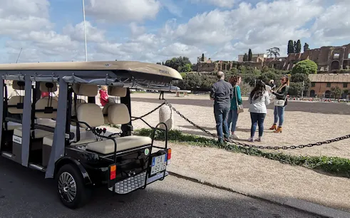 Golf cart parked near tourists at a historic site in Rome during a night tour.