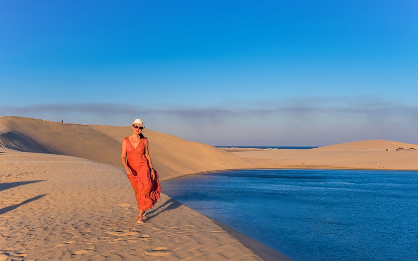 Woman walking along the inland sea in Doha desert landscape.