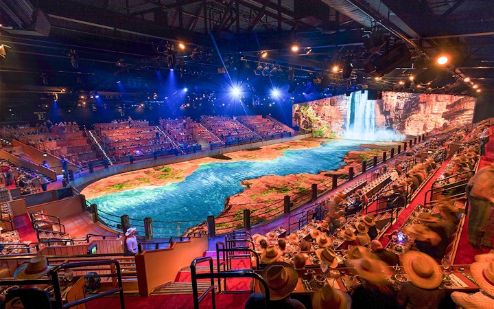 Audience watching Australian Outback Spectacular Heartland Dinner & Show with waterfall backdrop.