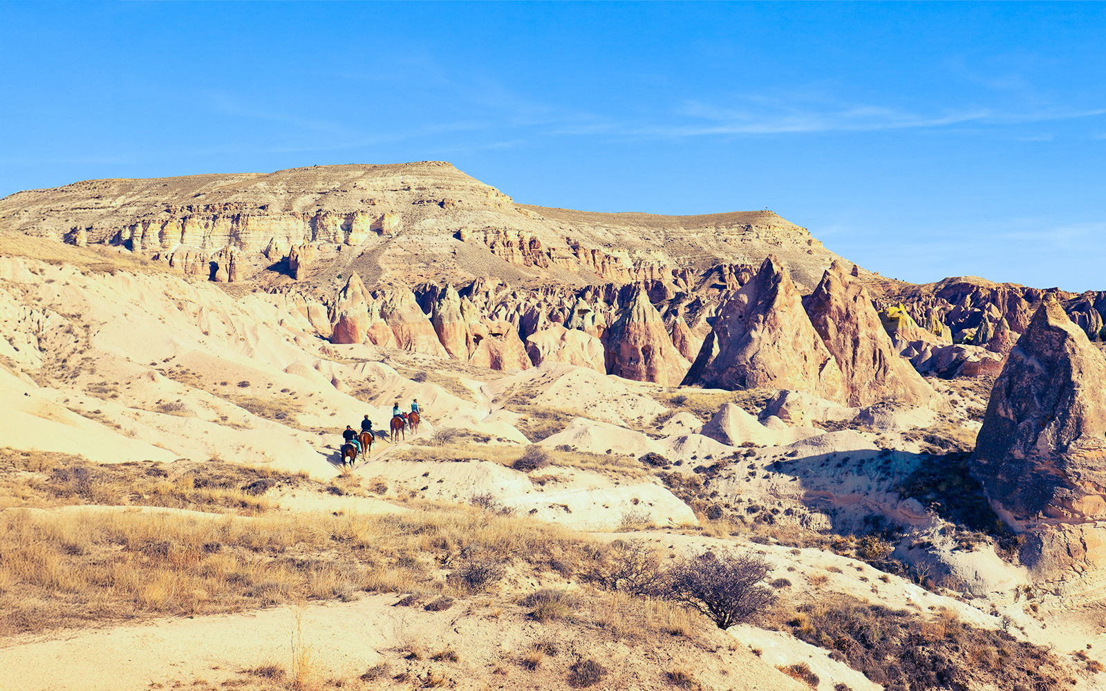 Horseback riders traverse Cappadocia's unique mountain valleys in Turkey.