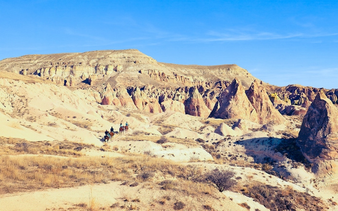 Horseback riders traverse Cappadocia's unique mountain valleys in Turkey.