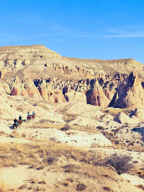 Horseback riders traverse Cappadocia's unique mountain valleys in Turkey.