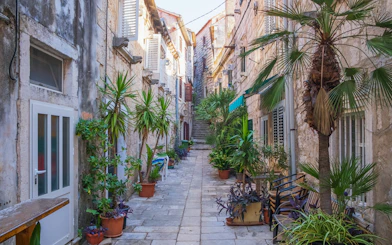 Romantic narrow street with stone buildings and potted plants in Pelješac, Dalmatia, Croatia.