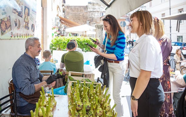 Man preparing artichokes during a guided street food tour in Campo de' Fiori, Rome.