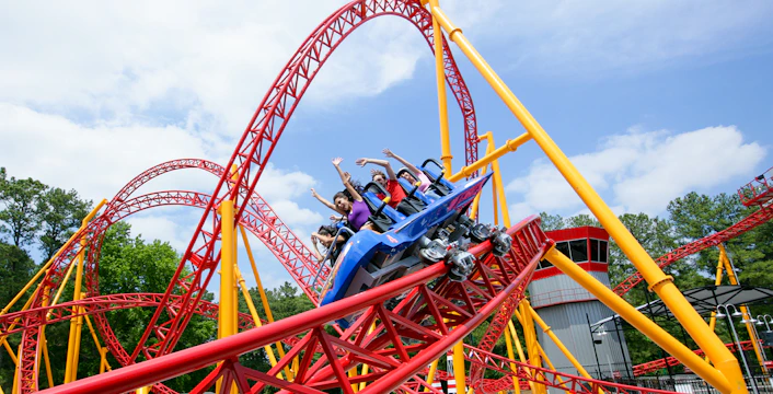 Dare Devil Rollercoaster with riders at Six Flags, Georgia, featuring red and yellow loops.
