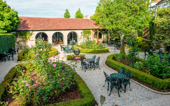 Outdoor garden seating at Taylor's Port Cellars in Porto with lush greenery and stone pathways.